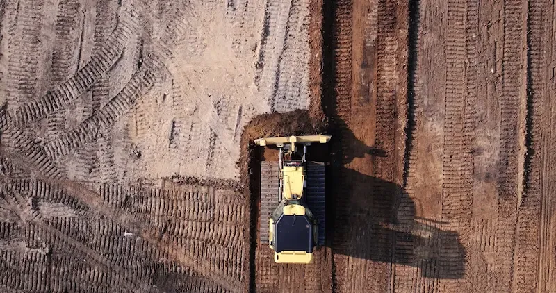 A bulldozer clearing dirt on a ball field.