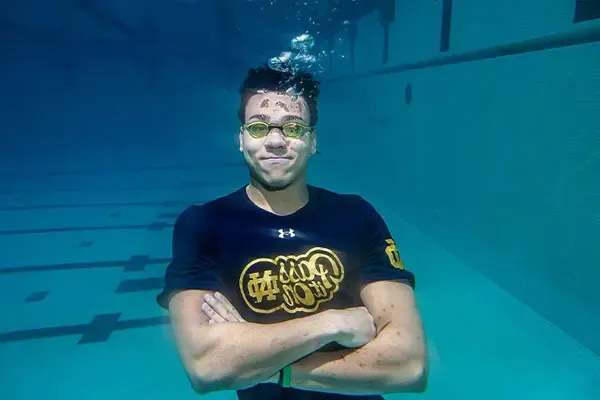 一名戴着护目镜的大学生双臂交叉，在水下漂浮
